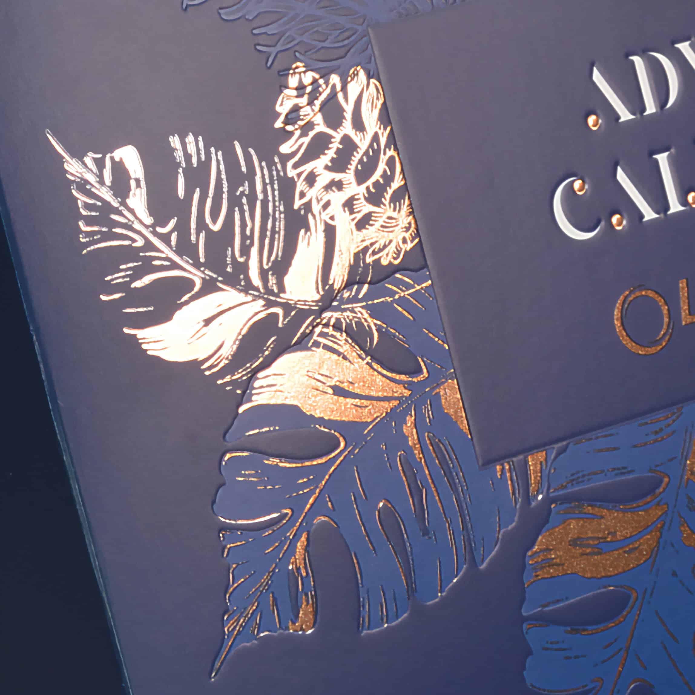 Detalle de caja azul con estampados en frío de hojas tropicales en foil dorado brillante.