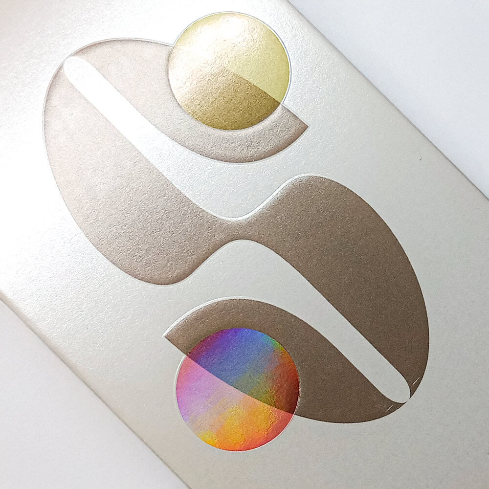Elementos geométricos con estampados holográficos que reflejan colores sobre un fondo blanco perlado.