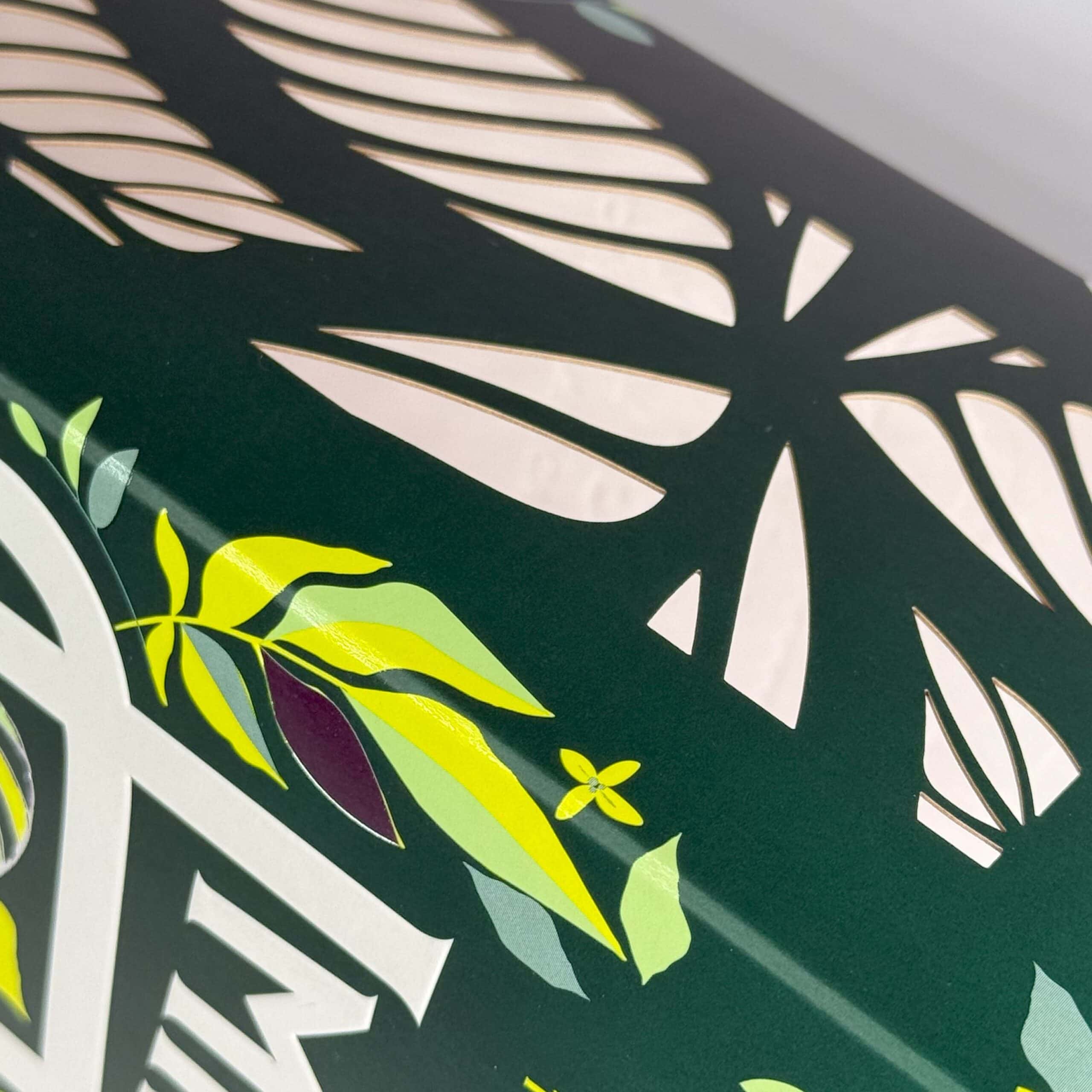 Detailed view of a green box with visual embossed packaging and laser-cut leaf patterns.
