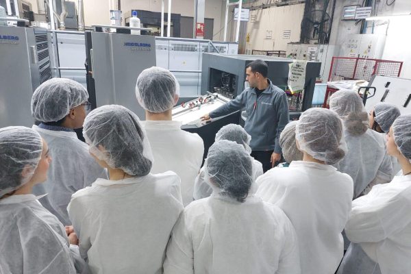Maquinaria de impresión y empaque en la planta de Leca Graphics, con empleados en formación y capacitación sobre procesos de fabricación de packaging de alta calidad.